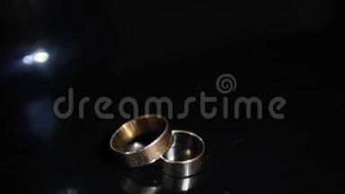 婚礼戒指黑色背景闪耀与轻珠宝关闭宏。 两个新娘和新郎的魅力戒指